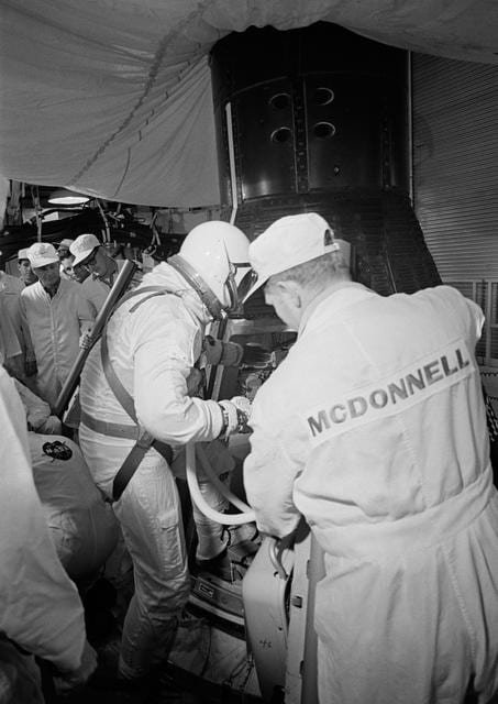 Astronaut John Young assisted into Gemini spacecraft in white room